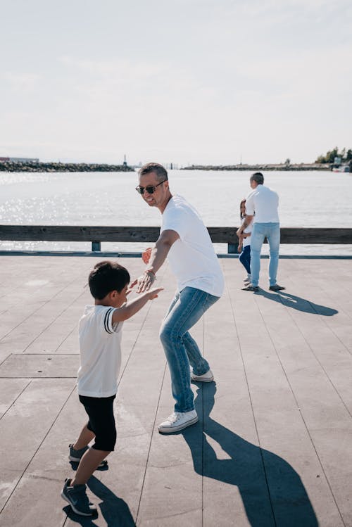 Free Dads Playing Together with Their Kids on Wooden Dock Stock Photo