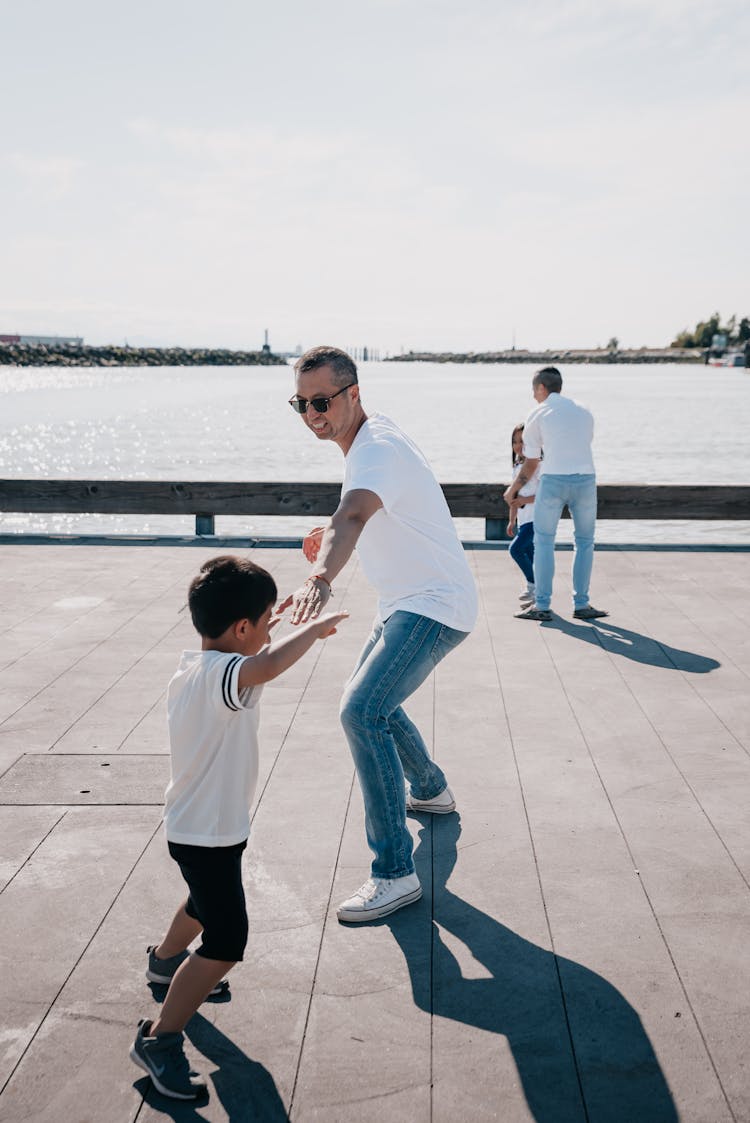 Dads Playing Together With Their Kids On Wooden Dock