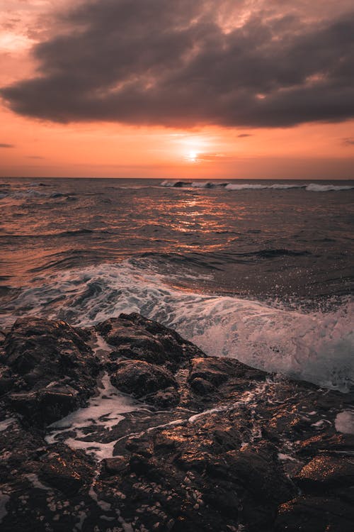 Waves Crashing on Rocks During Sunset