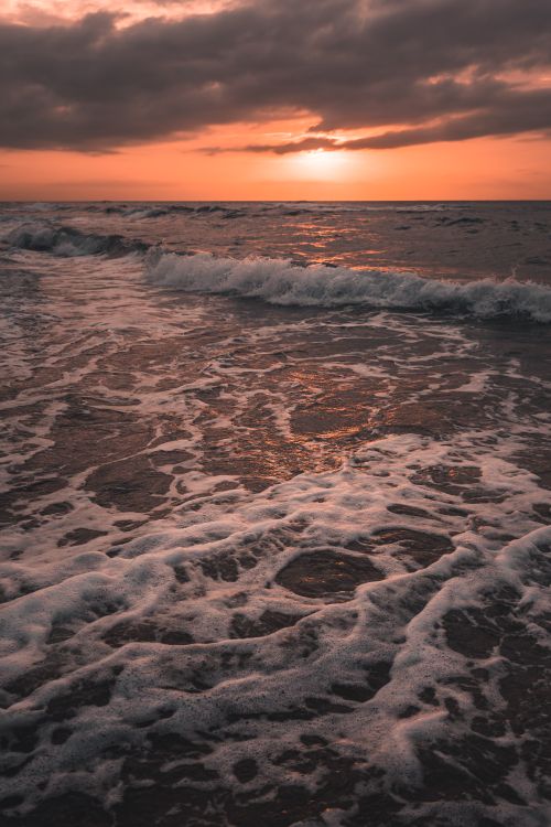 Free Captivating sunset over the ocean with dramatic crashing waves and golden hues. Stock Photo