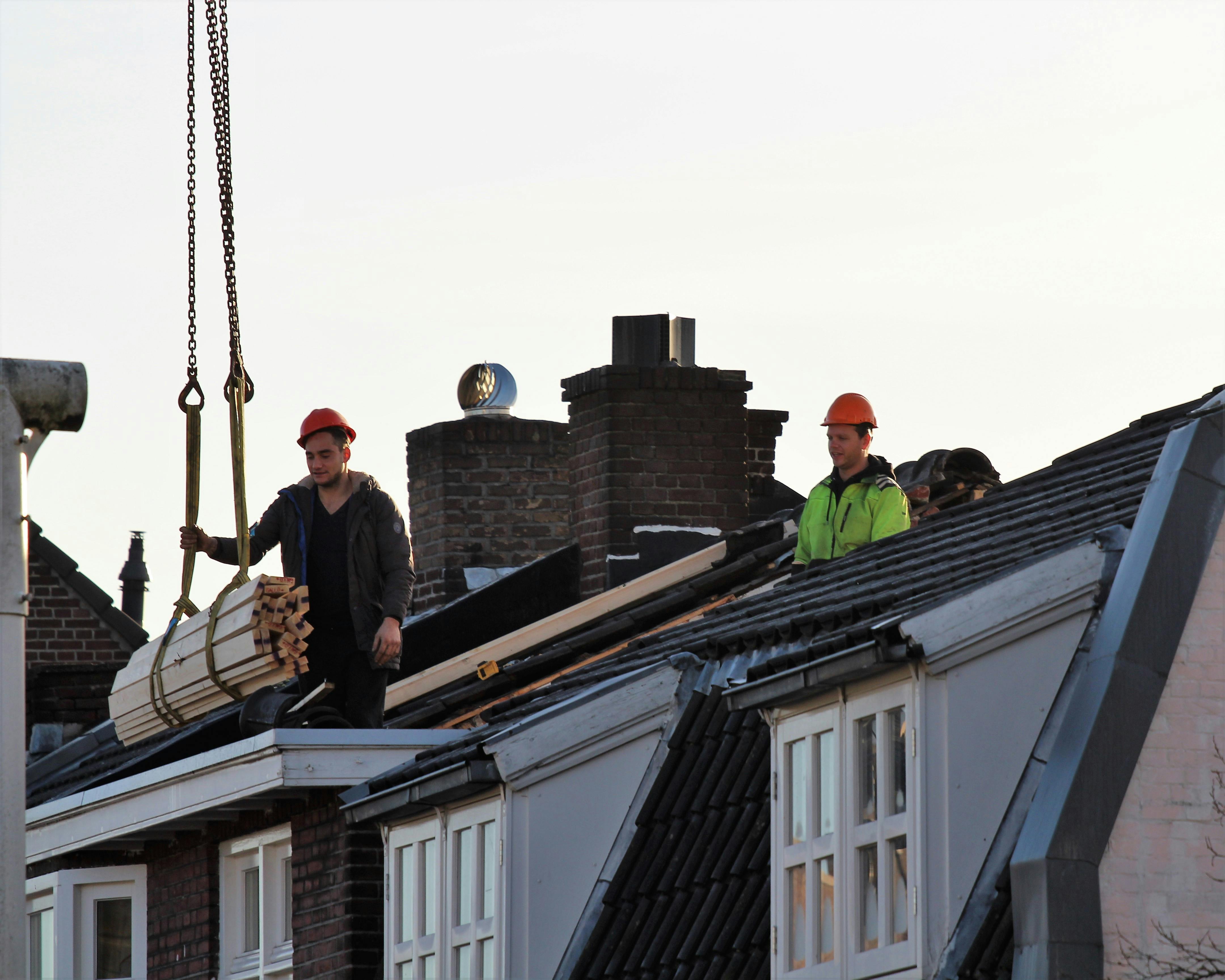 Workers operate on a rooftop under construction in the Netherlands, showcasing teamwork and safety.