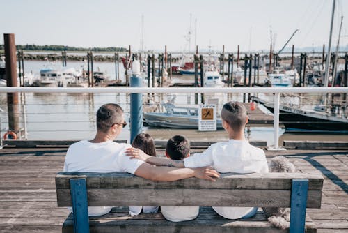 Back View of Family Sitting Close to Each Other on a Wooden Bench