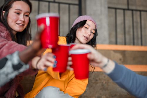 Free Group of young friends celebrating indoors with red cups, enjoying a casual gathering. Stock Photo
