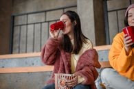 Woman in Brown Coat Drinking from Red Ceramic Mug