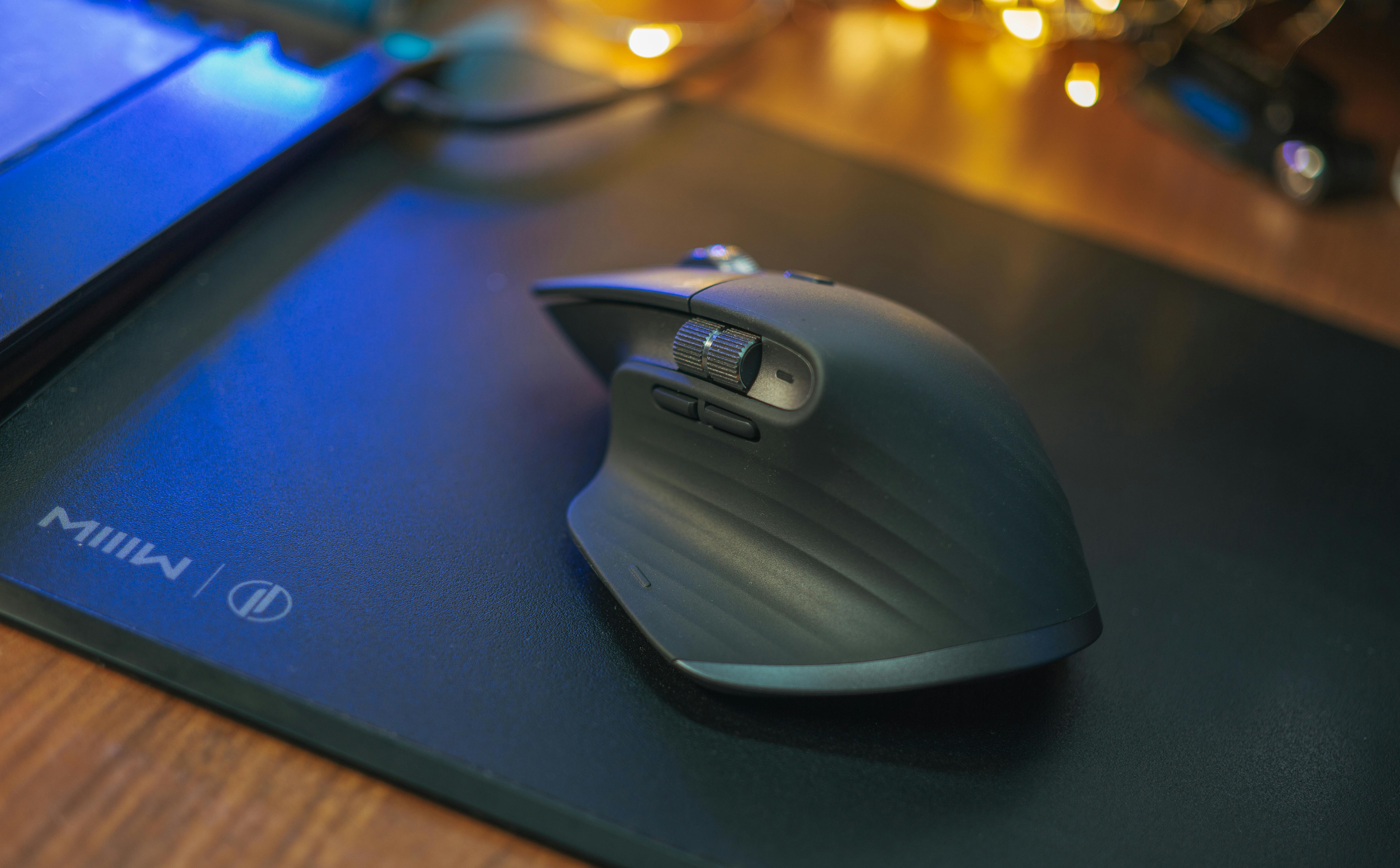 Stylish ergonomic wireless mouse on a sleek black mouse pad with ambient lighting.