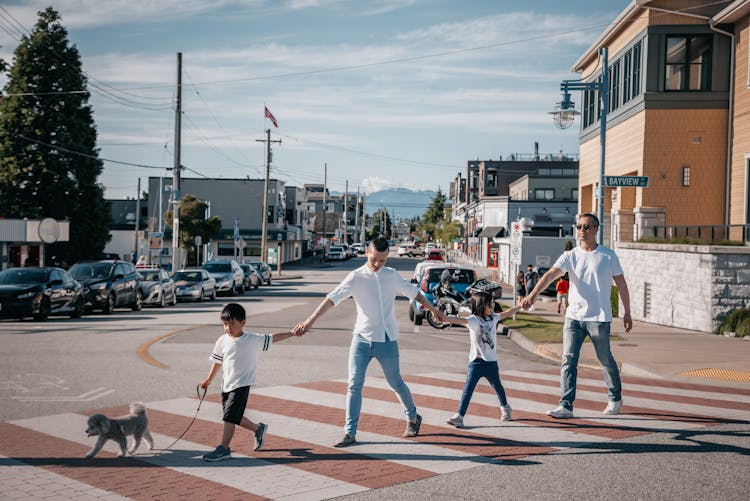 Family Crossing The Street While Holding Each Other's Hands