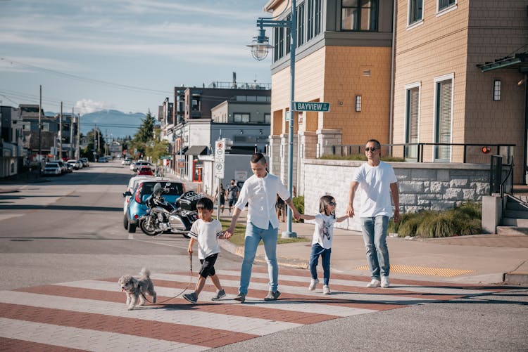 Family Crossing The Street While Holding Each Other's Hands