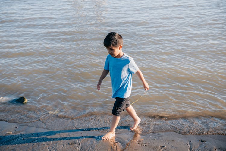 A Boy Walking At The Beach