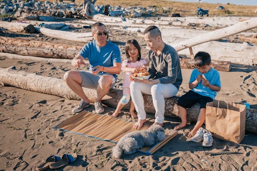 Family Sitting on a Log while Eating Snacks