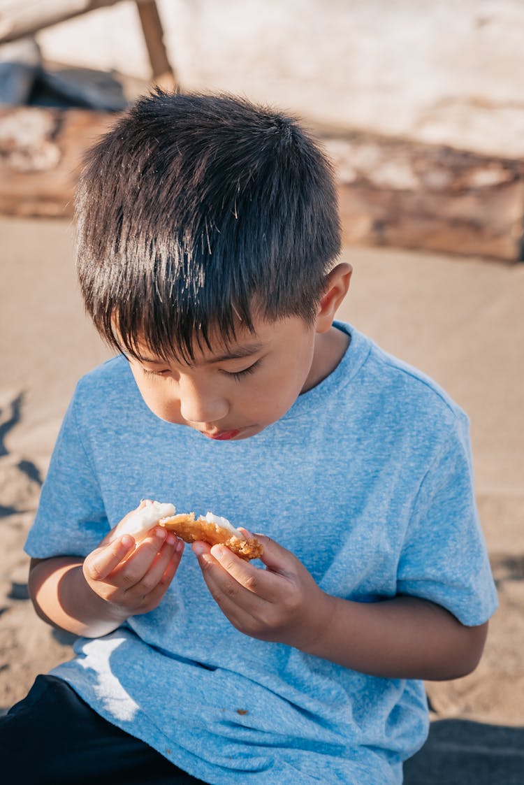 Boy In Blue Shirt Eating A Fried Food