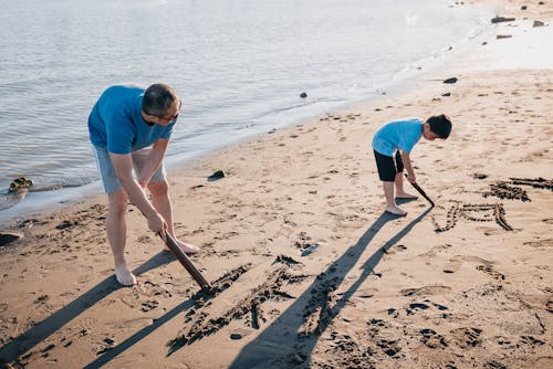 Father and Son Drawing on Sand 