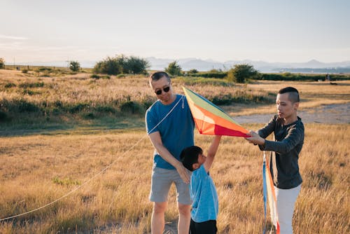 Free A Family Playing with Kite in the Grass Field Stock Photo