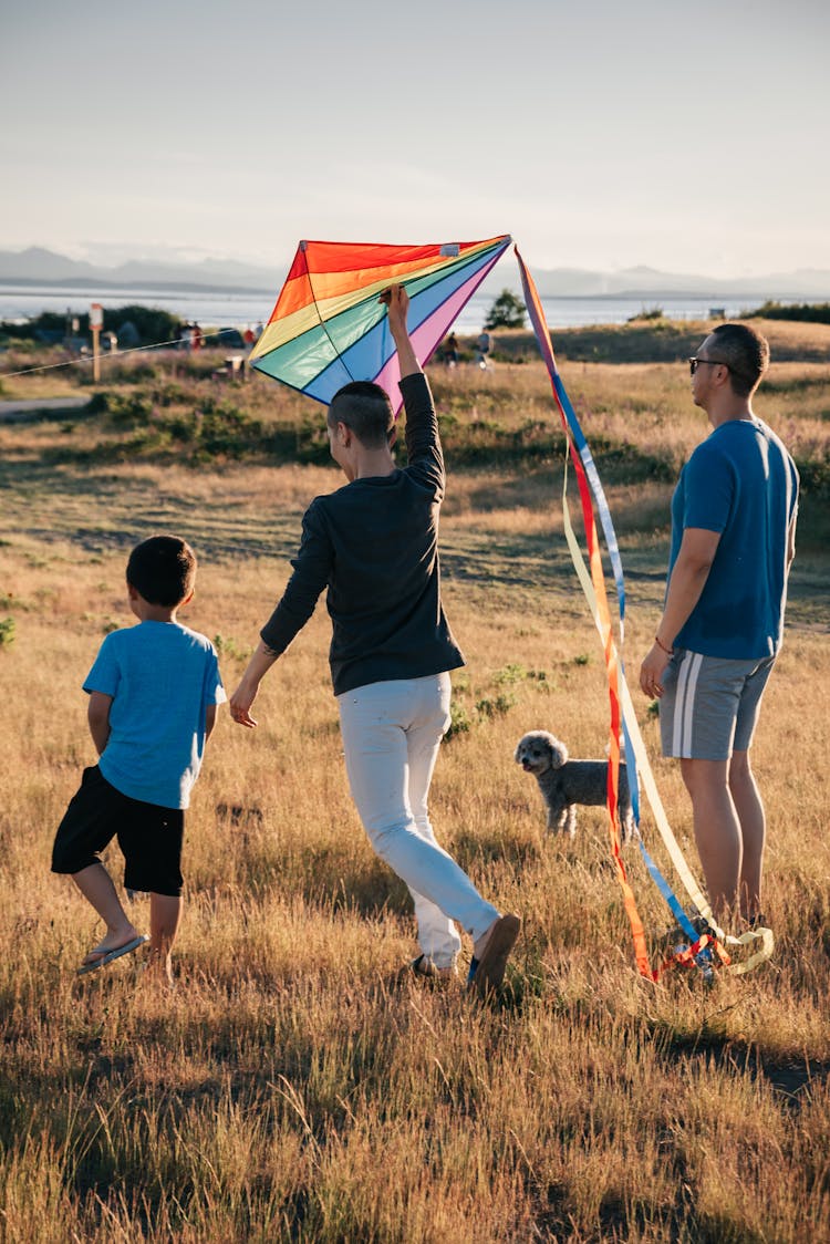 A Family Playing With Kite In The Grass Field