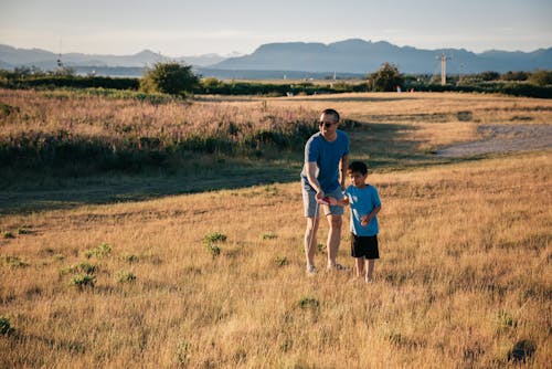 Free Dad and Son Having Fun Playing in the Grass Field Stock Photo