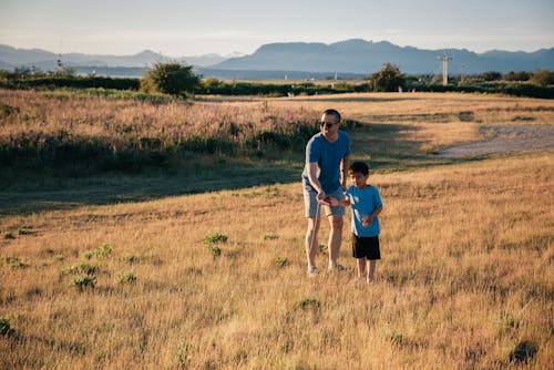 Dad and Son Having Fun Playing in the Grass Field