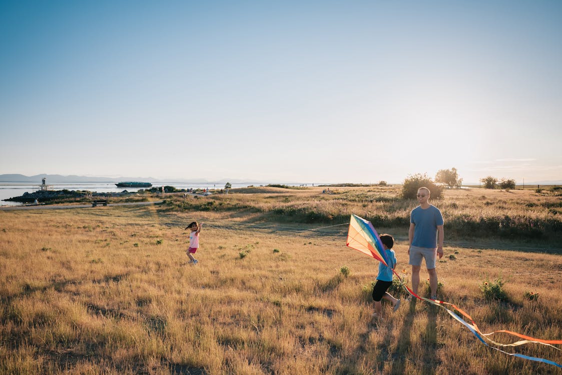 Free Happy Family Having Fun Playing with Kite on the Grass Field Stock Photo