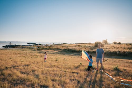 Happy Family Having Fun Playing with Kite on the Grass Field