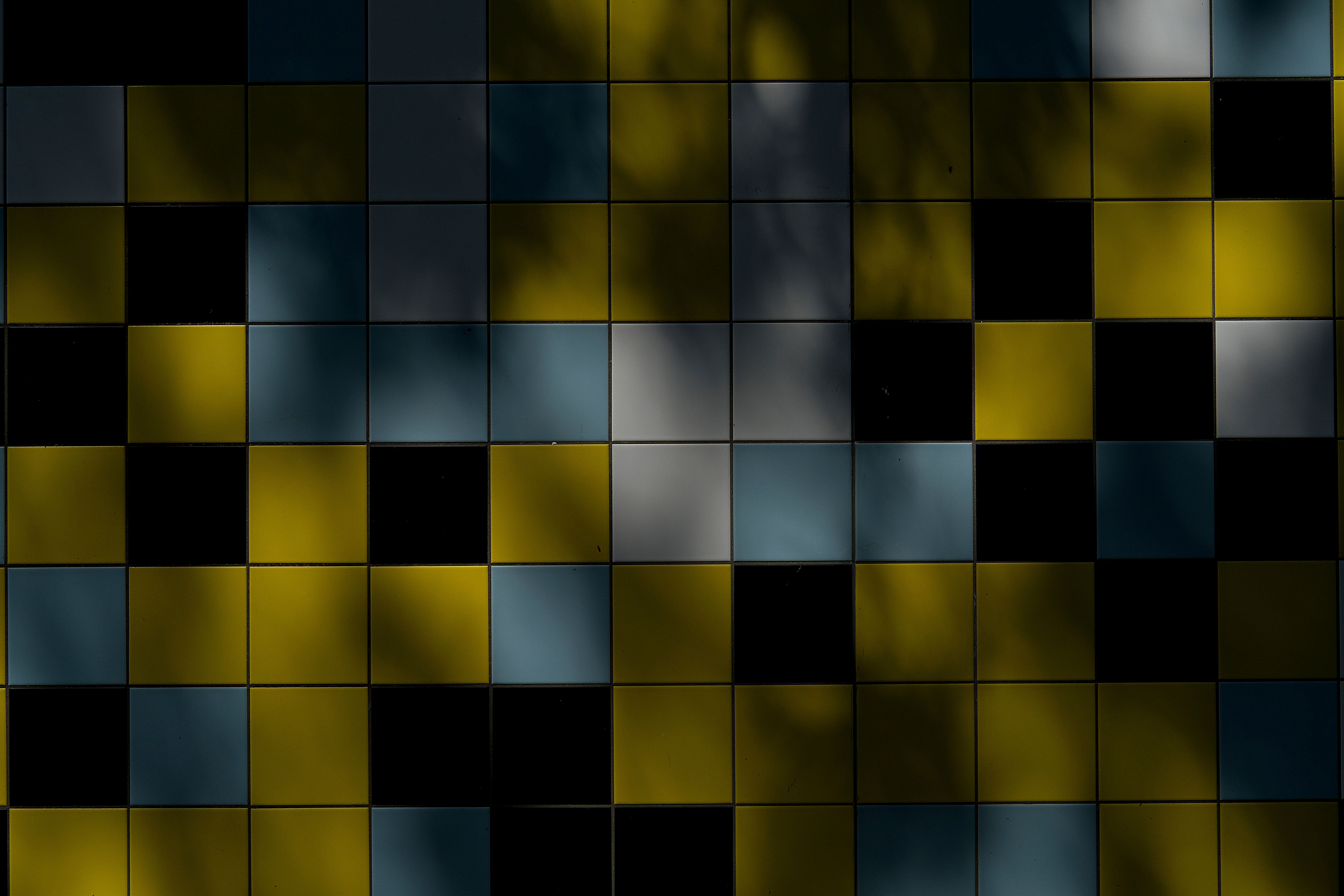 Vibrant tiled wall showcasing bold colors and shadow play, creating an abstract pattern.