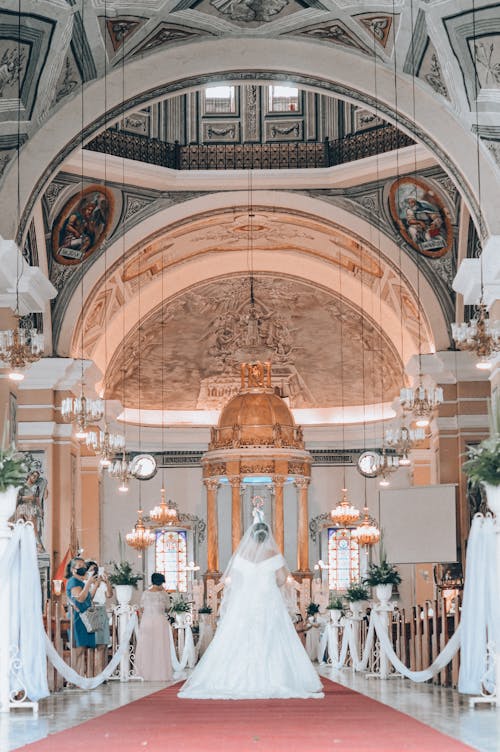 A Woman in White Dress Walking in the Aisle of the Church