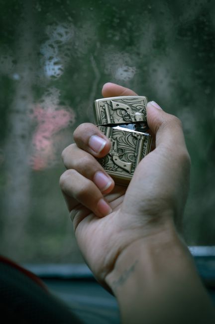 A detailed shot of a hand holding a decorative cigarette lighter with intricate designs.