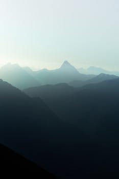 A tranquil view of the misty Swiss Alps with layers of mountains in twilight.
