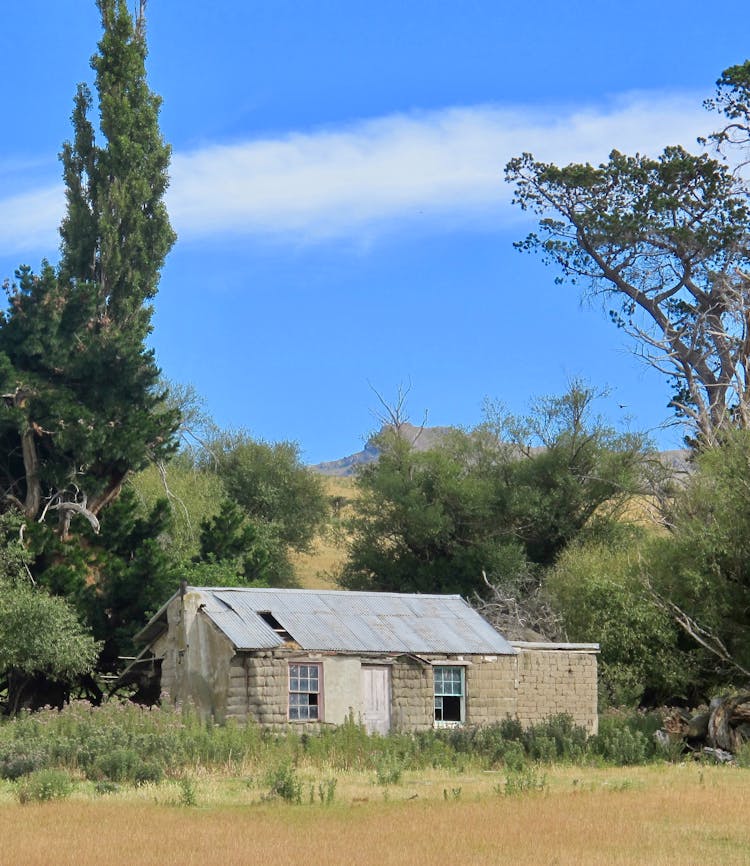 An Abandoned House With Broken Windows And Roof