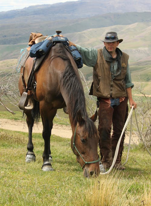 A Man Standing Beside the Brown Horse