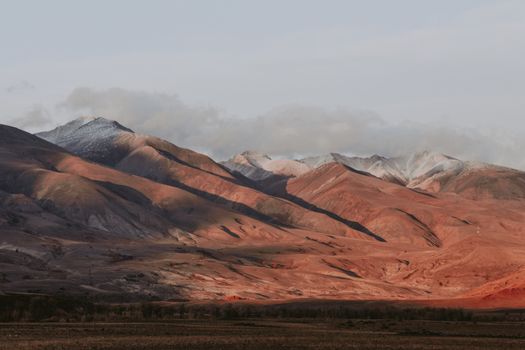 Breathtaking view of the rugged Altai mountain range at sunrise with dramatic lighting.