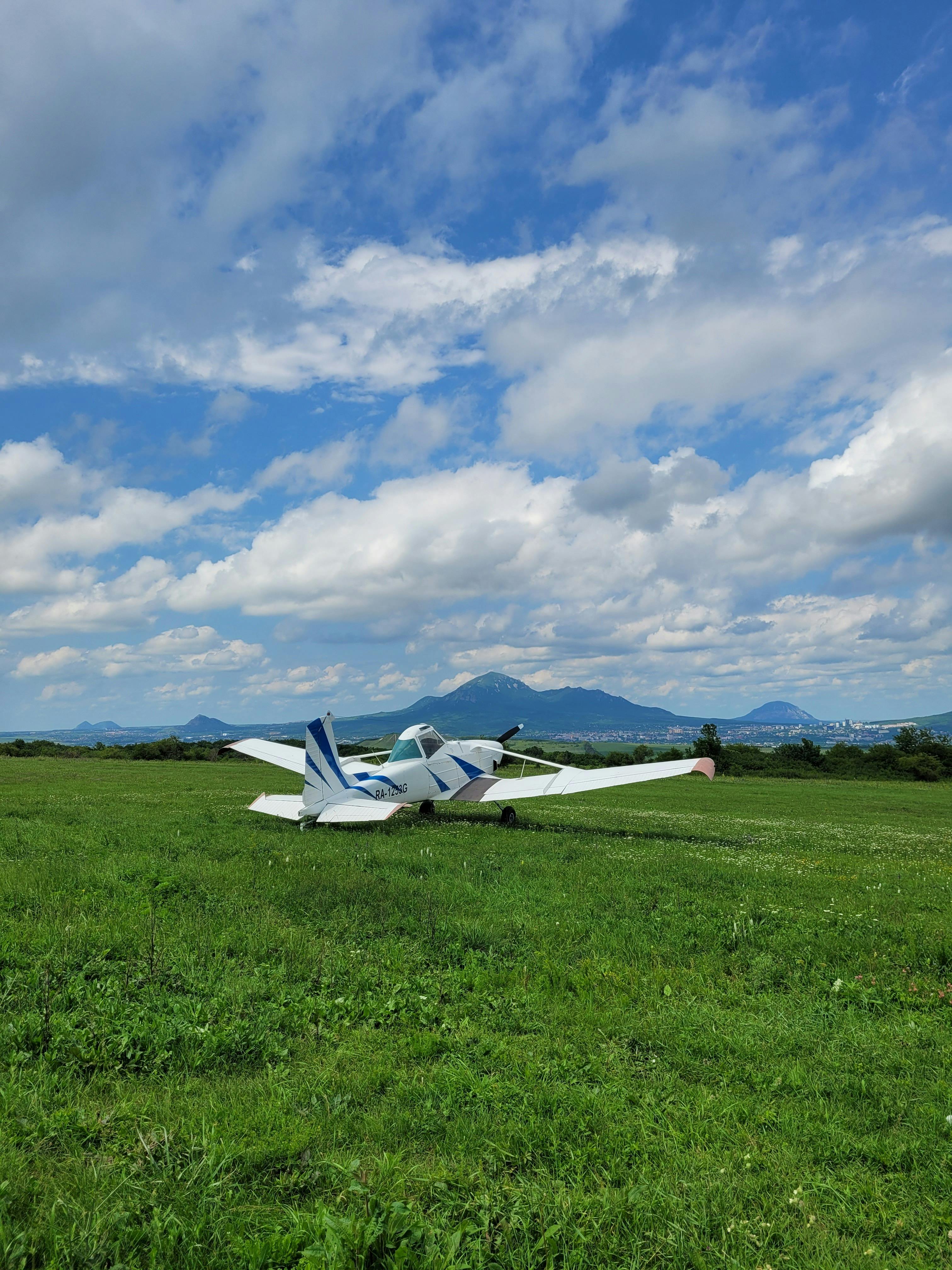 cessna plane parked on grass field under cloudy sky