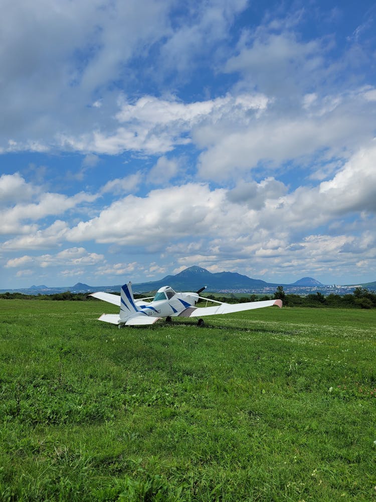 Cessna Plane Parked On Grass Field Under Cloudy Sky