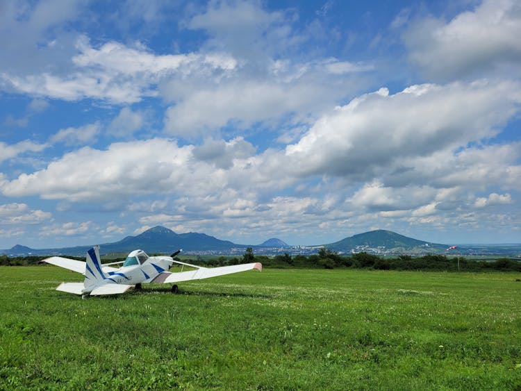 Cessna Plane Parked On Grass Field Under Cloudy Sky