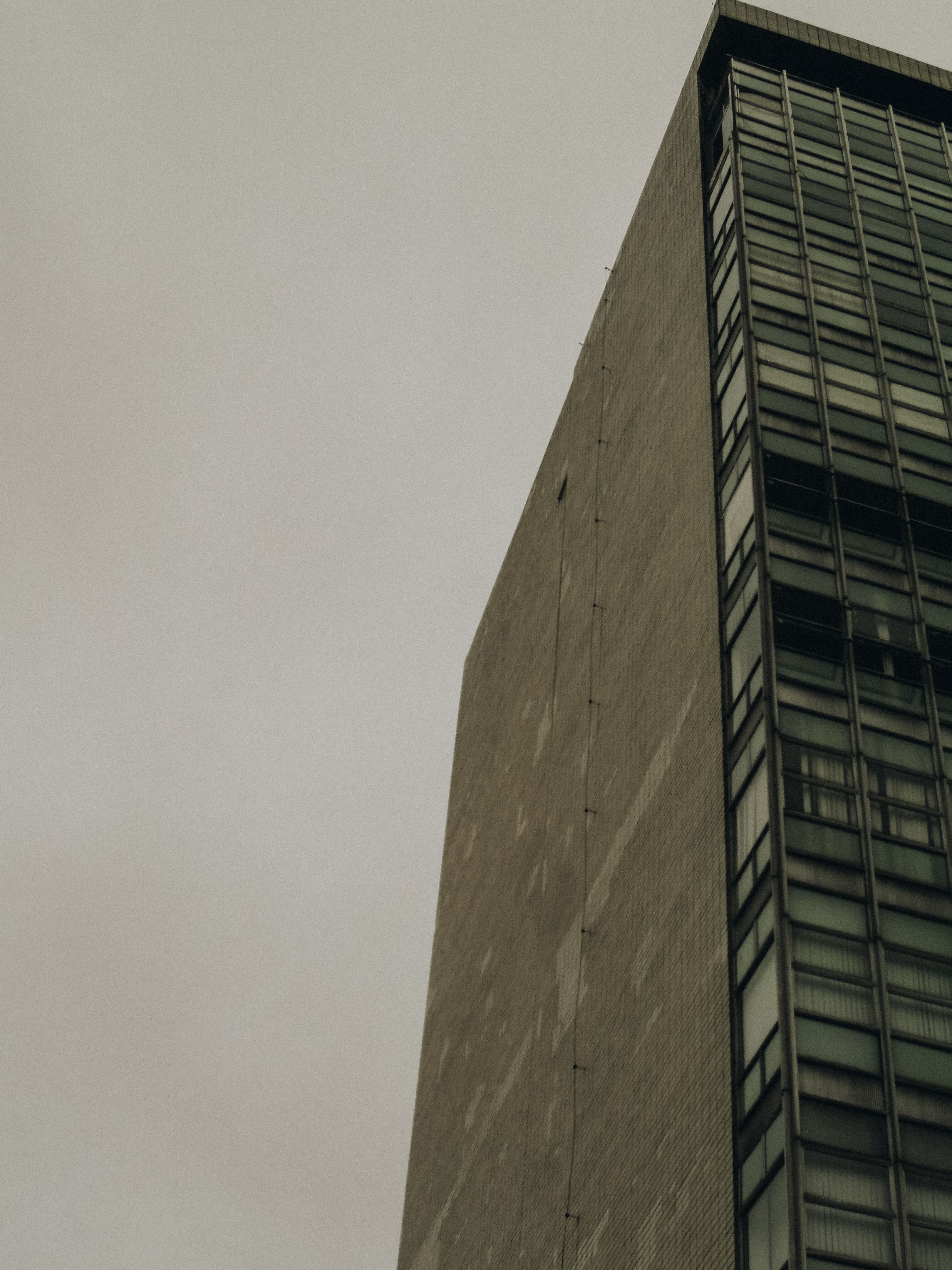 Low angle view of a modern high-rise building in Rio de Janeiro under an overcast sky.