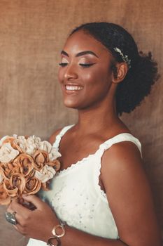Beautiful bride with afro hair smiling and holding a bouquet in Rio de Janeiro.