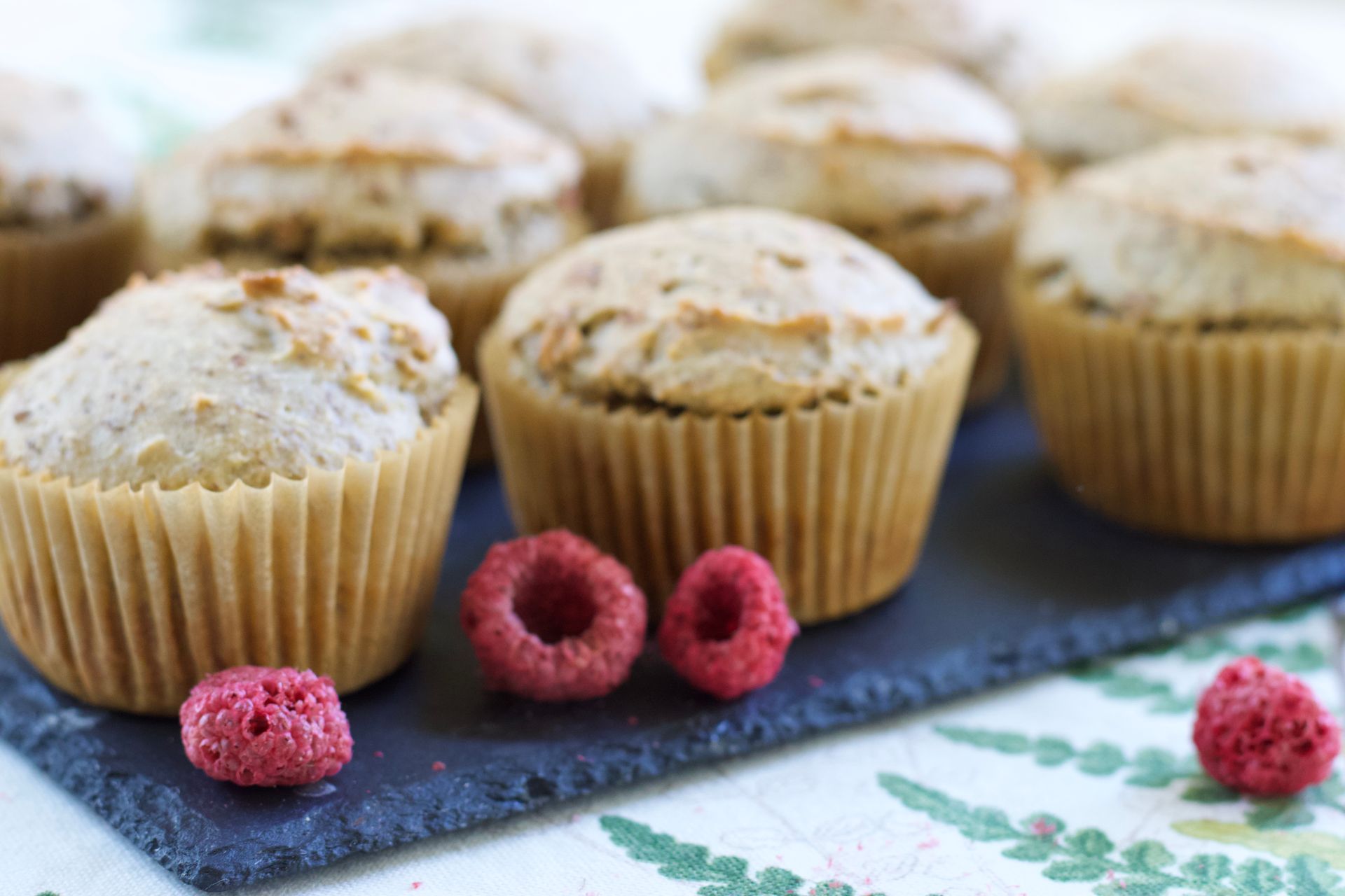 Delicious homemade muffins adorned with fresh raspberries on a slate plate. Perfect for a sweet breakfast treat.