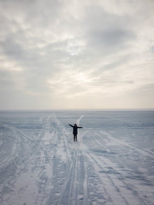 Person Standing with Arms Spread on a Field Covered in Snow 