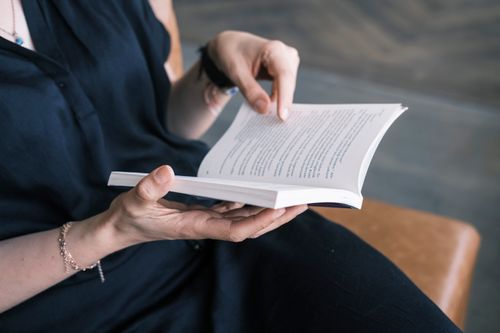 Free A person enjoys reading a book indoors with a focus on hands holding it. Stock Photo