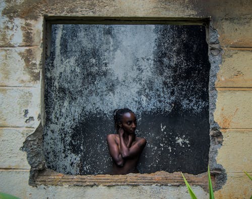 A Topless Woman Standing Beside Gray Concrete Wall