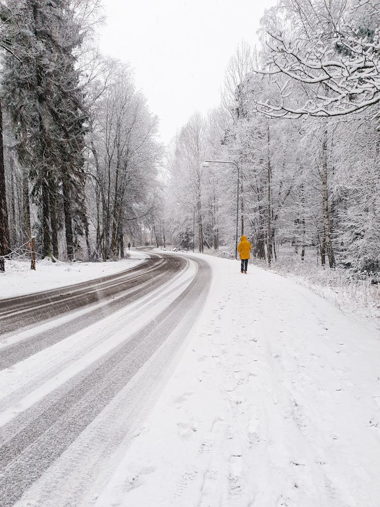 Man Walking On A Road Covered In Snow