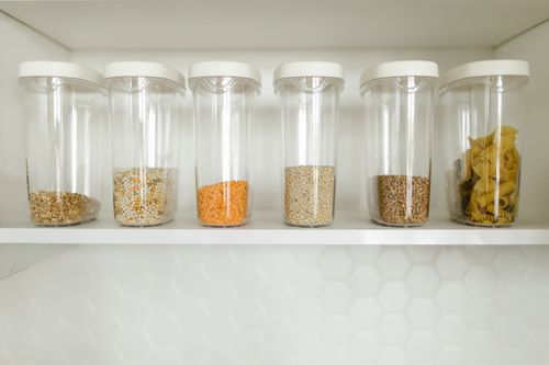 Free Clear containers filled with grains, pasta, and seeds, neatly organized on a shelf. Stock Photo
