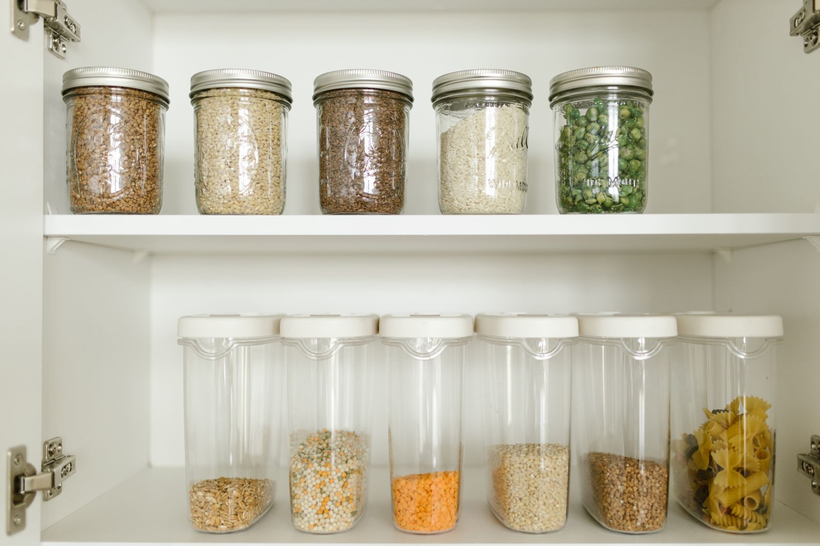 Dry goods in labeled glass containers on a pantry shelf.