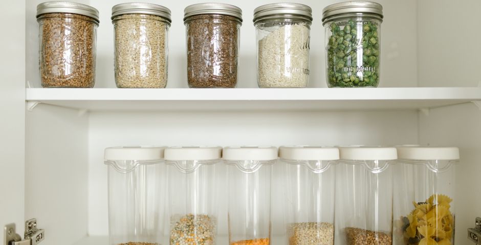 Dry goods stored in sealed glass containers on a pantry shelf, ready for a pest control visit