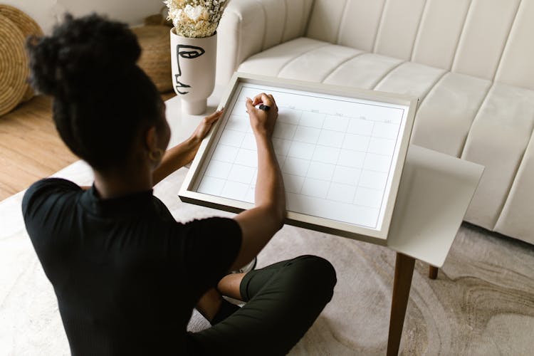 Back View Of A Woman Writing On A Calendar 