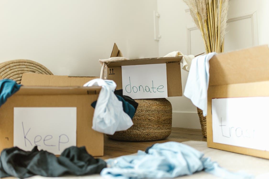 Free Cardboard boxes labeled keep, donate, and trash for effective home organization. Stock Photo