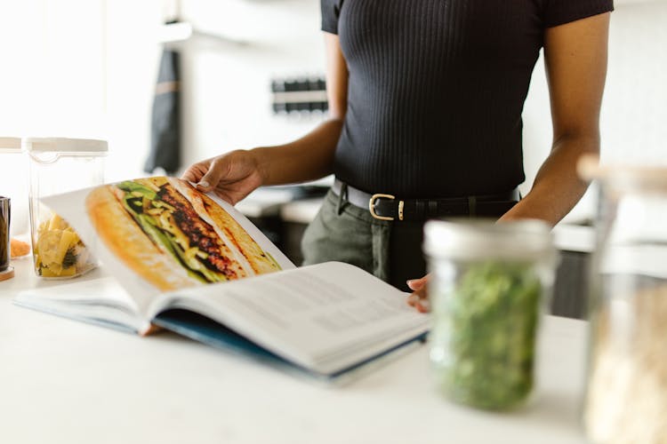 Person Looking For Recipes On A Food Magazine 