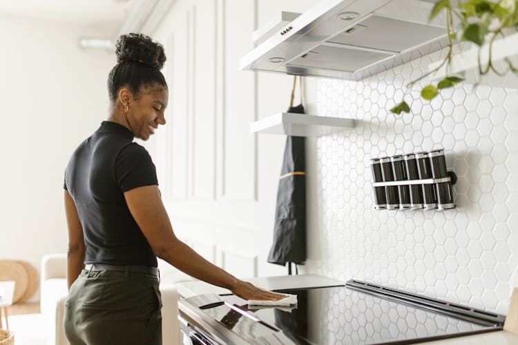 Responsible Woman Wiping An Electric Stove Clean 