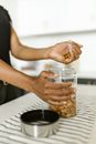 A Person Putting Almonds in a Glass Jar