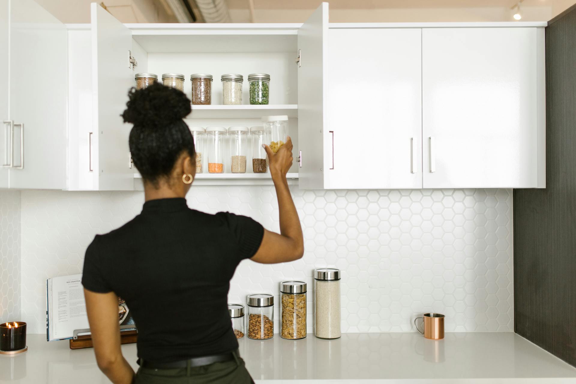 Woman putting Glass Containers on a Kitchen Cabinet