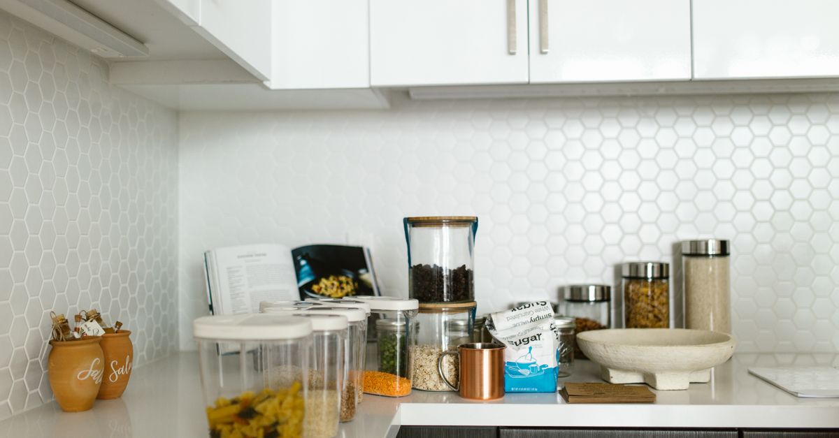 A clean, organized kitchen with labeled meal prep containers for athletes, with a parent or chef packing them into a cooler