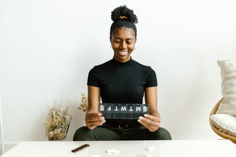 Smilign Woman Looking At A Medicine Organizer 