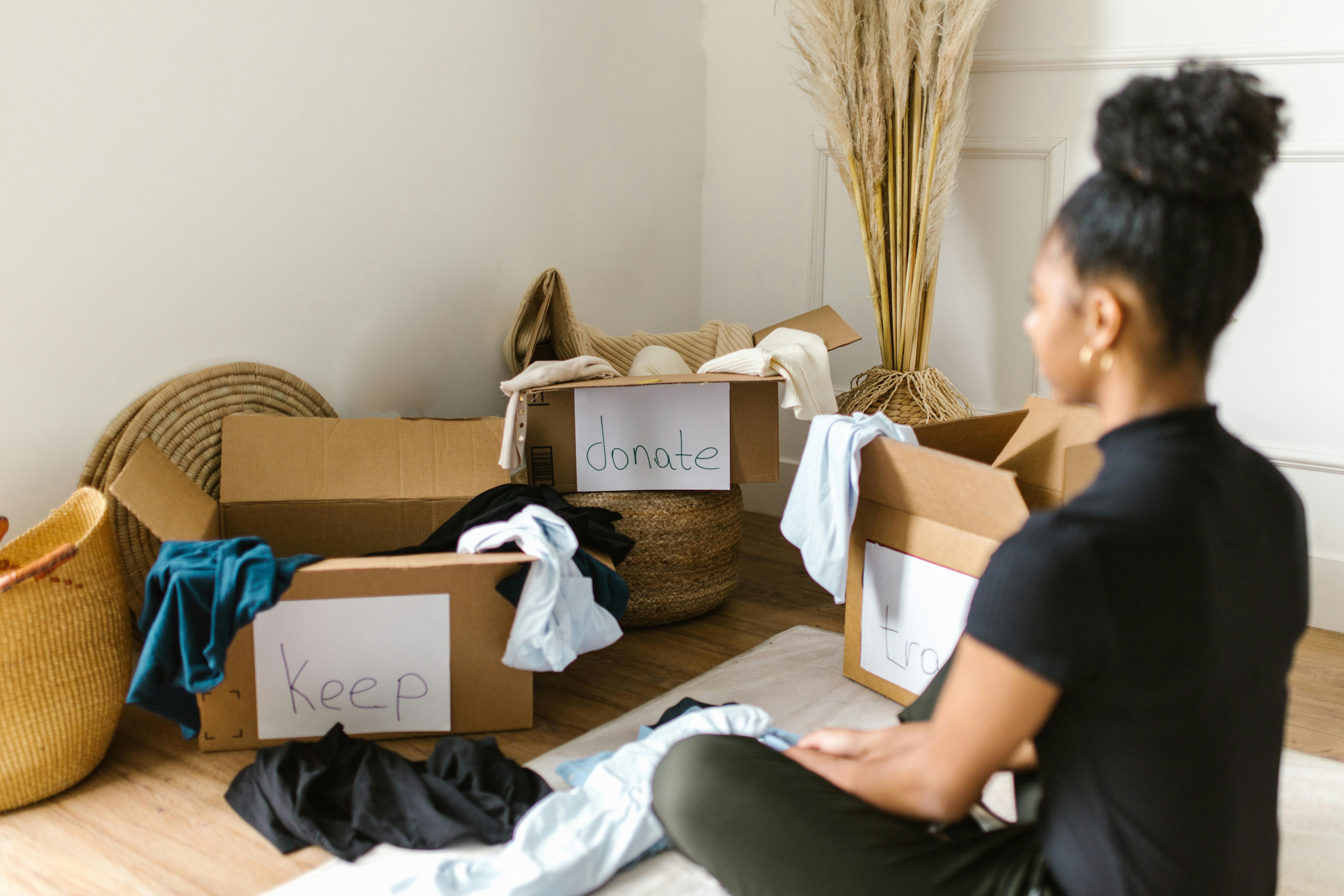 A person sitting in front of cardboard boxes with clothes in them